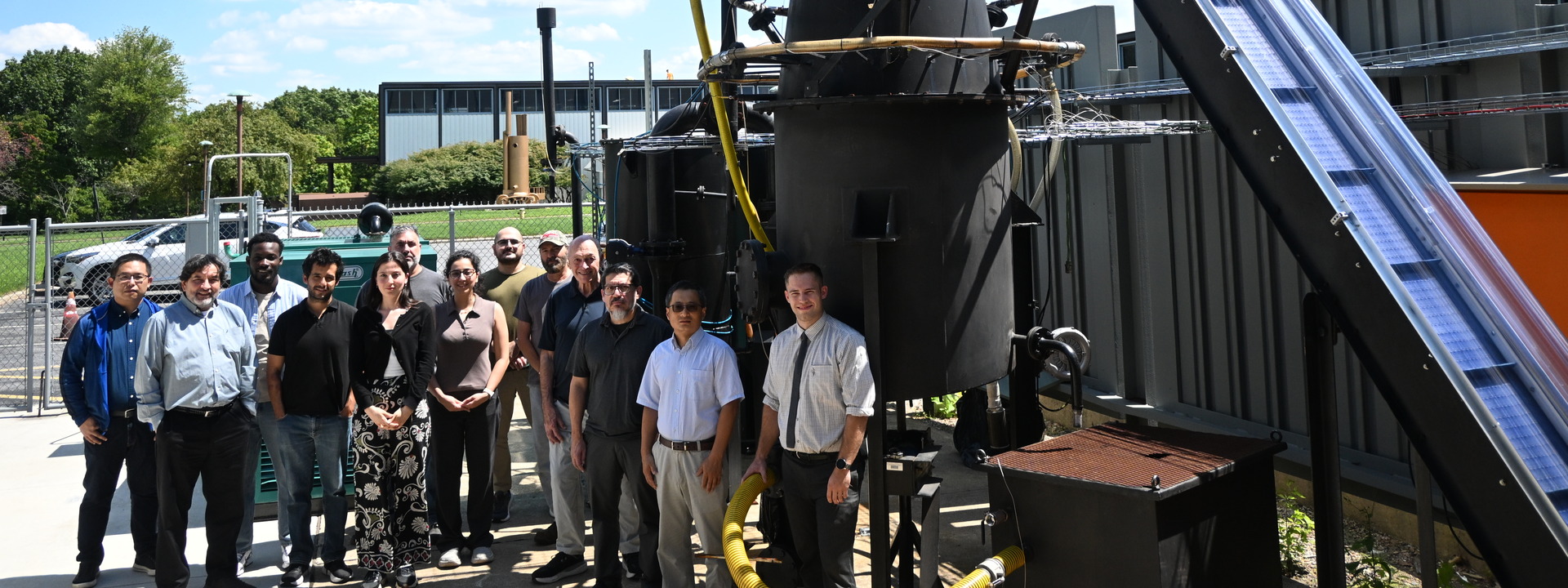 The research team poses next to the gasifier