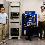 Zhen and Romero stand next to the cabinet, laser, and fuel source for their ML-Enhanced LIBS.