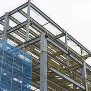 A tall building under construction, showing beams and nets