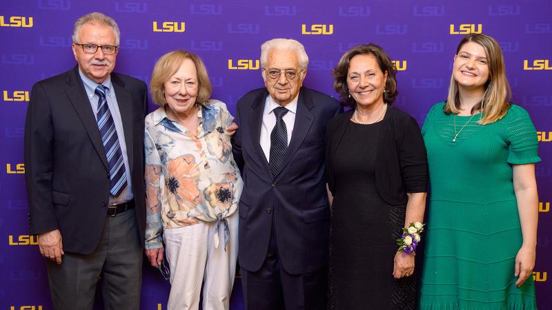 Pamukcu posing with a group of people in front of an LSU step-and-repeat
